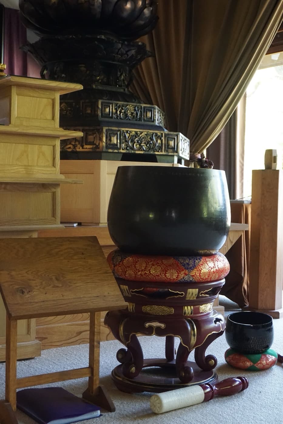 A brass singing bowl resting on a patterned cushion