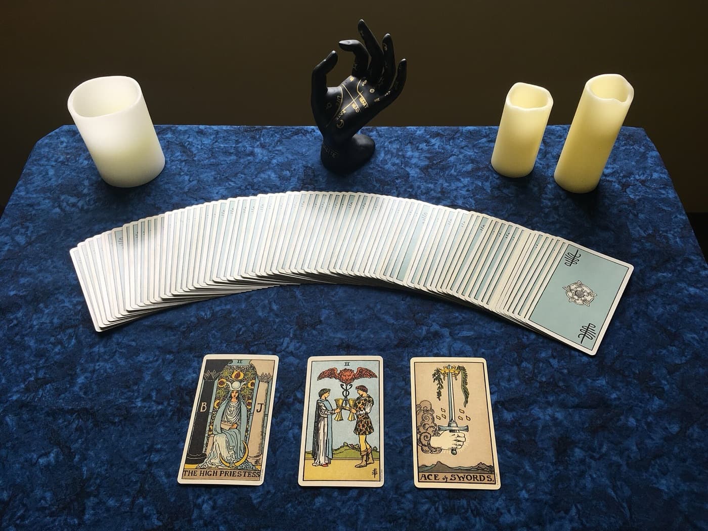 A three card tarot spread laid out beside lit candles